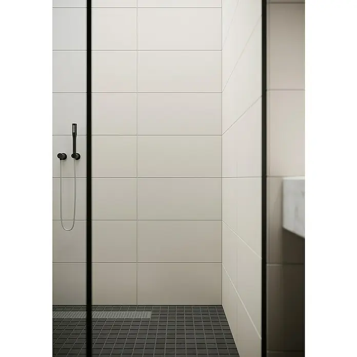 Ambiente by Palazzo Wandfliese Soft Sand - 30 x 60 cm, Creme, Matt - Detailaufnahme einer modernen Dusche mit mattschwarzer Handbrause und grauen Fliesen. Minimalistisches Baddesign.
