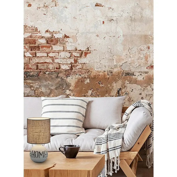 Reality Leuchten Lámpara de sobremesa redonda Esna Home - Home, 40 W, Ø x Al: 165 mm x 31 cm, Gris/Marrón, E14 - Primer plano de una lámpara decorativa Home con pantalla marrón sobre una mesa de madera, con un sofá y una pared de ladrillo al fondo.