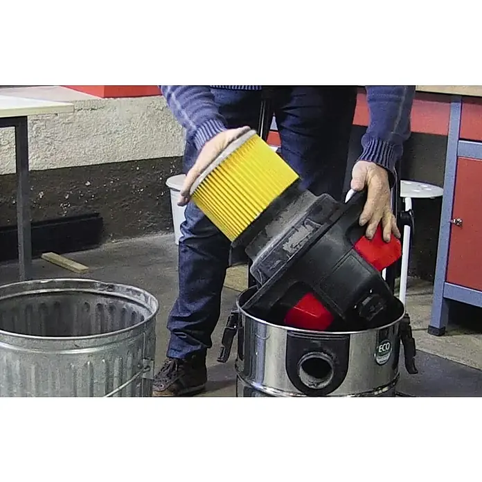 Einhell FaltenfilterDurchmesser: 190 mm - Ein Mann leert einen Staubsauger mit einem gelben Filter über einem Metalleimer.