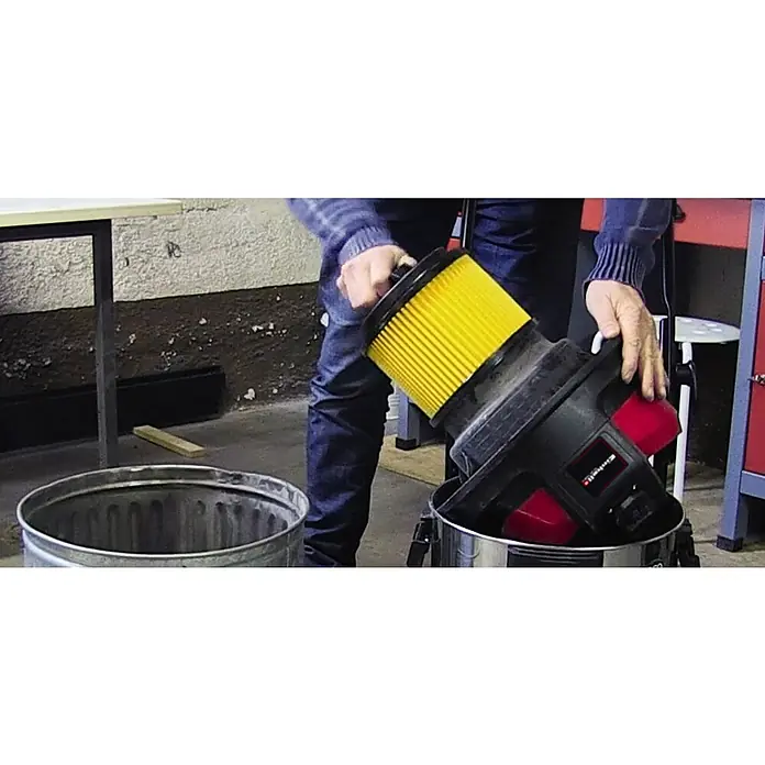 Einhell Faltenfilter Faltenfilter mit Schraubdeckel - Passend für: Einhell Nass-/Trockensauger - Entleerung eines Einhell Nass-Trockensaugers in einen Mülleimer, wobei der gelbe Filter gut sichtbar ist. Das Gerät ist rot und schwarz.