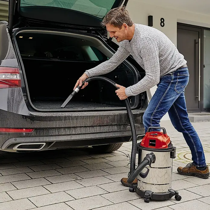 Einhell Elektro-Nass- & Trockensauger - 1.250 W, Behältervolumen: 20 l - Mann saugt den Kofferraum eines schwarzen Autos mit einem Einhell Nass-Trockensauger aus. Perfekt für die Autoreinigung.