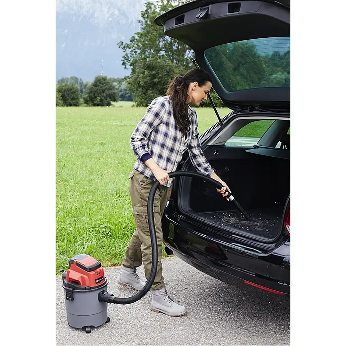 Einhell Power X-Change 18V Akku-Nass-Trockensauger TC-VC 18/15 Li-Solo - 18 V, Ohne Akku, Behältervolumen: 15 l - Eine Frau reinigt mit einem Einhell Nass-Trockensauger den Kofferraum ihres Autos, während sie im Freien steht.