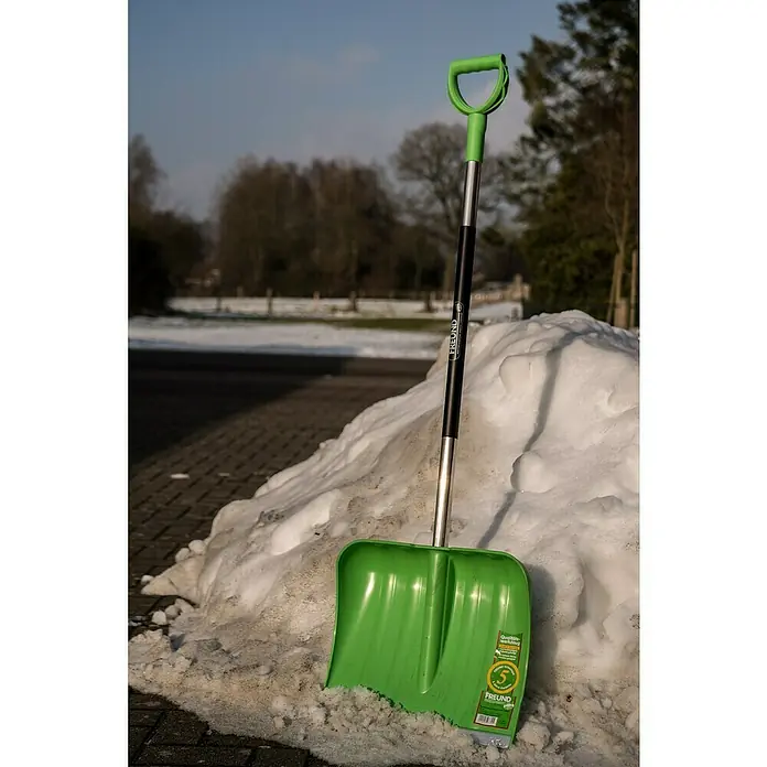 Freund Victoria Kunststoff-Schneeschaufel - Breite: 40 cm, Material Stiel: Aluminium - Grüne FREUND Schneeschaufel lehnt an einem Schneehaufen, bereit für den Wintereinsatz. Ideal für Hausbesitzer und Winterdienste.