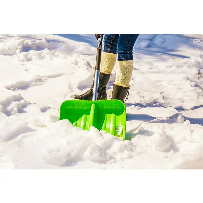 Freund Victoria Kunststoff-Schneeschaufel - Breite: 40 cm, Material Stiel: Aluminium - Eine Person schaufelt Schnee mit einem grünen Freund Schneeschieber. Die Schaufel sticht im weißen Schnee hervor.