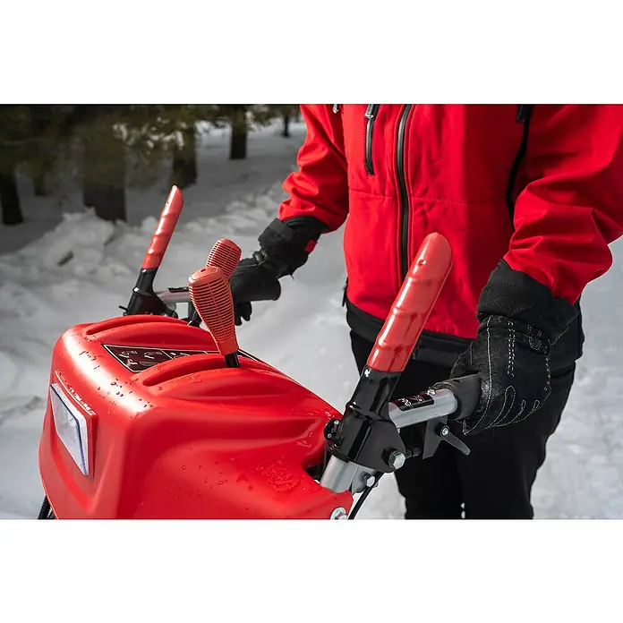 AL-KO Premium Benzin-Schneefräse SnowLine 620 E III - 6,2 kW, 302 cm³, Arbeitsbreite: 62 cm - Nahaufnahme einer Person, die eine rote Schneefräse mit schwarzen Handschuhen bedient. Die Fräse steht im Schnee.