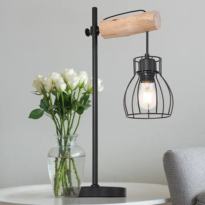 Globo Mina Tischleuchte - 40 W, L x B x H: 33 x 18 x 55 cm, E27 - Eine stilvolle Tischleuchte mit einem Holzbalken und einem schwarzen Metallkäfig um die Glühbirne. Sie steht neben einer Vase mit weißen Rosen.