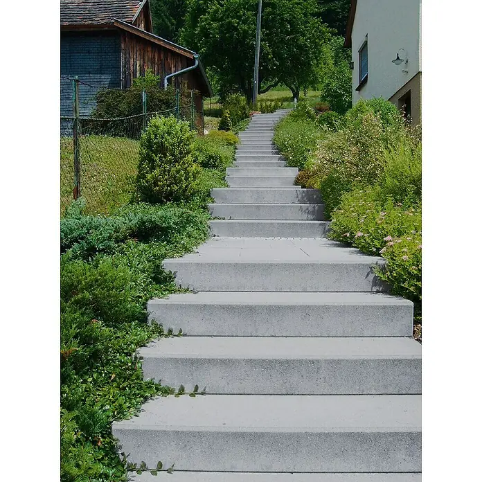 Diephaus Blockstufe - 100 x 36 x 16 cm, Grau, Beton - Eine lange, graue Betontreppe führt einen grünen Hügel hinauf, der von üppigem Grün und Vegetation gesäumt ist.
