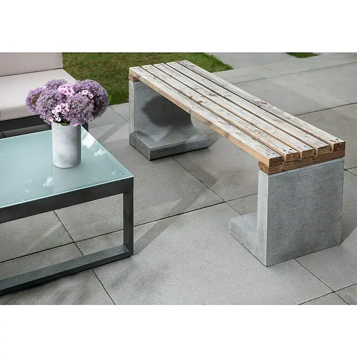 Diephaus L-Stein - 30 cm, 40 cm, Stärke: 7 cm, Grau - Eine stilvolle Gartenszene mit einer modernen Bank aus Holz und Beton, einem Glastisch und einem Blumenarrangement.