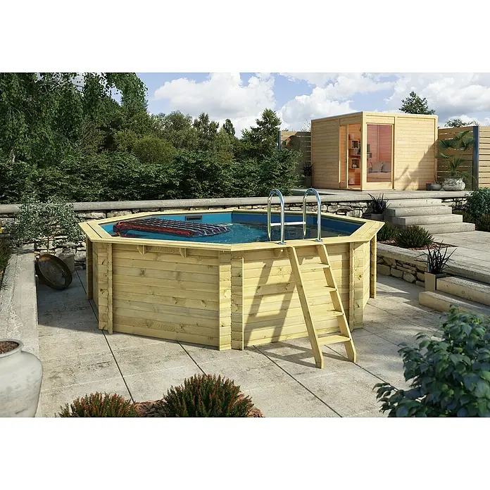 Karibu Holz-Pool Orlando Größe 2 - L x B x H: 470 x 470 x 124 cm, Naturbraun, 16.000 l, Ohne Poolterrasse - Ein hölzernes Schwimmbecken im Garten, mit einer Leiter und einer Plane darauf. Im Hintergrund befindet sich ein kleines Holzhaus.