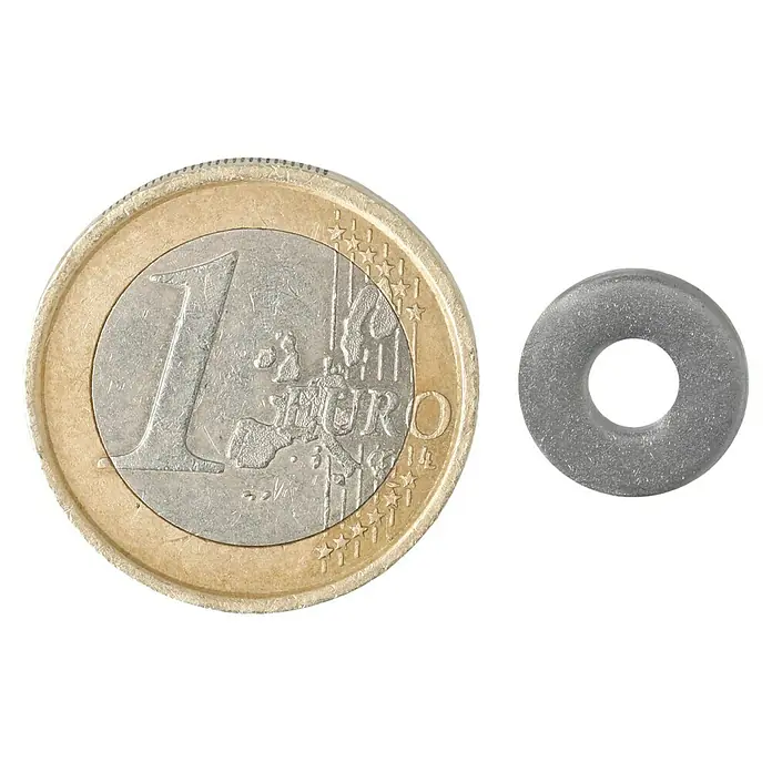 Profi Depot Bauscheibe A2 - Außendurchmesser: 12 mm, 100 Stk., Edelstahl - Ein Euro-Münze liegt neben einer kleinen, grauen Unterlegscheibe auf schwarzem Hintergrund, zur Größenvergleich.