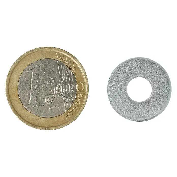 Profi Depot Bauscheibe VZ - 6,4 mm, 100 Stk., Verzinkt - Ein Euro-Stück liegt neben einer Metallscheibe auf schwarzem Grund. Die Scheibe ist hell und hat ein Loch in der Mitte.