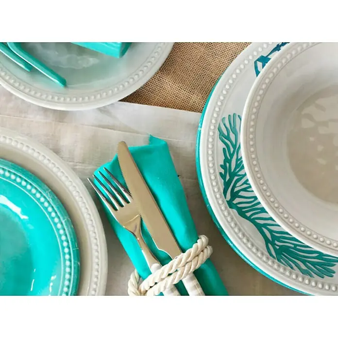 Marine Business Harmony Plato redondo - 6 ud., Diámetro: 21 cm, Plástico, Perla - Una mesa con temática náutica que presenta platos turquesas, vajilla blanca y una servilleta con un anillo de cuerda para una estética marina.