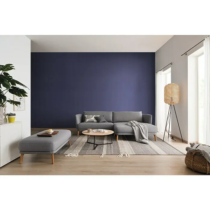 SCHÖNER WOHNEN-Farbe Mix Wandfarbe Glimmerfarbe zum Mischen lassen - Basismischfarbe 2, Matt, 2,5 l, Lösemittelfrei - Wohnzimmer mit grauem Sofa, Ottomane, Couchtisch und einem auffälligen Korbgeflecht-Lampenschirm vor einem Fenster.