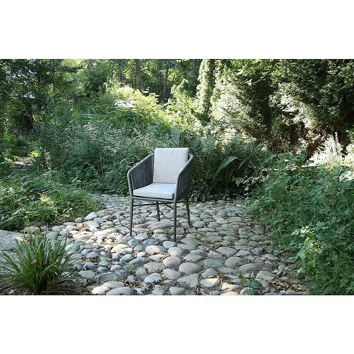 Acamp Gartensessel Manhattan Set - 6 Stk., Aluminium, Polyester, Stapelbar, Grau, B x T x H: 61 x 63 x 81 cm - Ein einzelner grauer Sessel mit hellgrauem Kissen steht auf einem steinigen Weg in einem üppigen Garten. Der Sessel lädt zum Verweilen ein.