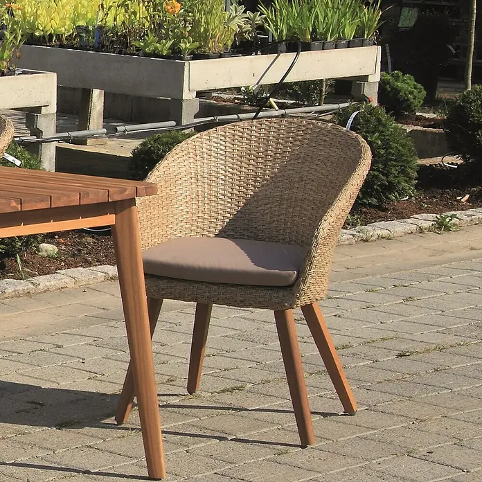 Acamp Gartenmöbel-Set Atacama - 5 -tlg., Aluminium, Polyrattan, Polyester, Braun - Nahaufnahme eines Korbstuhls mit hellbraunem Sitzkissen und Holzbeinen neben einem Holztisch im Freien.