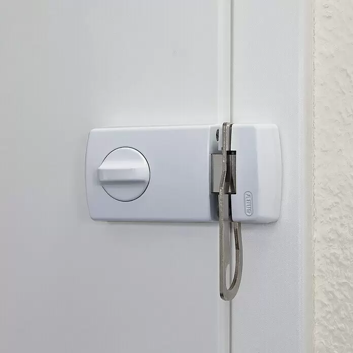 Abus Türzusatzschloss 2130 - Silber, Geeignet für: Nach innen öffnende Eingangstüren - Weißes ABUS Türsicherheitsschloss mit Drehknauf, eine Metallstange am Türrahmen sichernd.