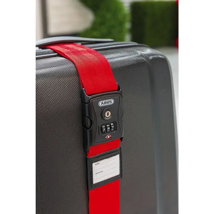 Abus Zurrgurt 620 TSA - Länge: 192 cm, Anzahl Zahlenrollen: 3 Stk., Rot - Nahaufnahme eines schwarzen Koffers mit einem roten ABUS Gepäckgurt und Zahlenschloss für sicheres Reisen.