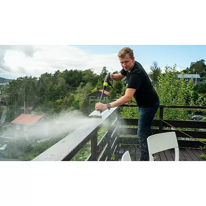 Ava Reinigungsbürste - Geeignet für: Gartenmöbel, Passend für: Ava Hochdruckreiniger - Mann reinigt ein dunkles Holzgeländer mit einem Hochdruckreiniger, Wasser spritzend.