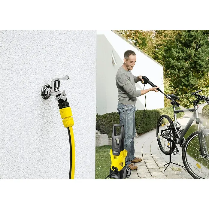 Kärcher Hidrolimpiadora de alta presión K 3 - 120 bar, 1.600 W, Capacidad de bombeo: 380 l/h - Hidrolimpiadora en acción: Un hombre limpia una bicicleta al aire libre con una Kärcher amarilla.