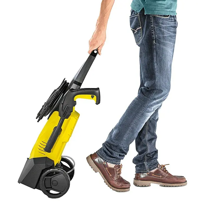 Kärcher Hidrolimpiadora de alta presión K 3 - 120 bar, 1.600 W, Capacidad de bombeo: 380 l/h - Una persona tira de una hidrolimpiadora de alta presión Kärcher amarilla con asa negra y ruedas sobre un fondo blanco.