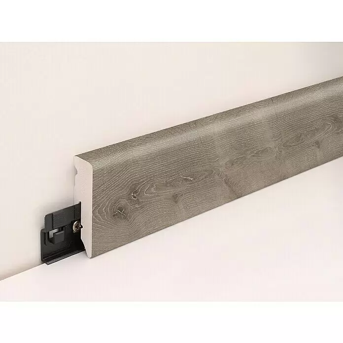 Profiles and more Sockelleiste KU051L Canyon Oak - 240 cm x 15 mm x 50 mm - Grau melierte Sockelleiste in Holzoptik mit sichtbarem Befestigungsclip und Schraube an der Wand.