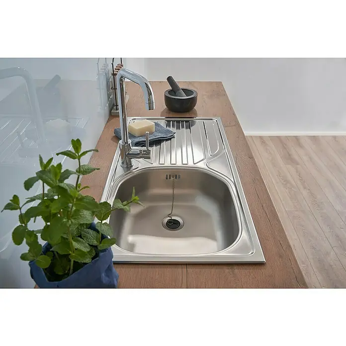 Respekta Einbauspüle - 86 x 43,5 cm, Edelstahl, Edelstahl - Edelstahlspüle mit Abtropffläche, Wasserhahn, Seife, Mörser und frischer Minze. Die Spüle ist sauber und glänzend und wirkt einladend.