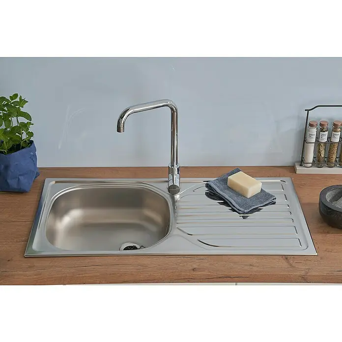 Respekta Einbauspüle - 86 x 43,5 cm, Edelstahl, Edelstahl - Spültisch aus Edelstahl mit Abtropffläche, Armatur, Seife und Handtuch auf einer hölzernen Arbeitsplatte. Die Spüle ist sauber und modern.