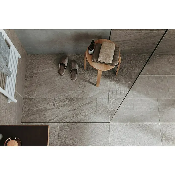 Atlas Concorde Solution Valmalenco Mosaikfliese Grigio - 30 x 30 cm, Grau, Matt - Draufsicht auf ein stilvolles Badezimmer mit Steinzeugfliesen, einem Hocker mit Handtüchern und Hausschuhen für einen luxuriösen Touch.