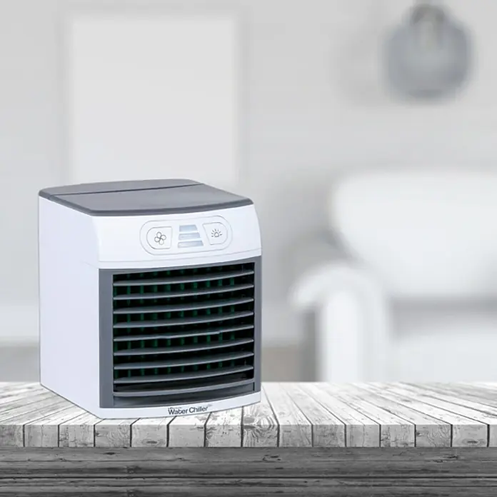 Aire acondicionado portátil Eco Water Chiller - Blanco - Primer plano de un "Water Chiller" portátil con detalles grises, colocado sobre una mesa de madera frente a un fondo borroso.