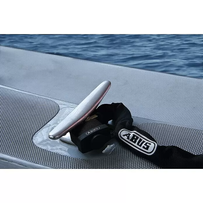 Abus Vorhängeschloss Aqua Safe 70IB/45 Gleichschließend - B x H: 49 x 74 mm, Bügelstärke: 8 mm, Messing, Schwarz - Schwarze ABUS Sicherheitskette und Vorhängeschloss an einer silbernen Bootsklampe auf einem grauen Bootsdeck, mit blauem Wasser im Hintergrund befestigt.