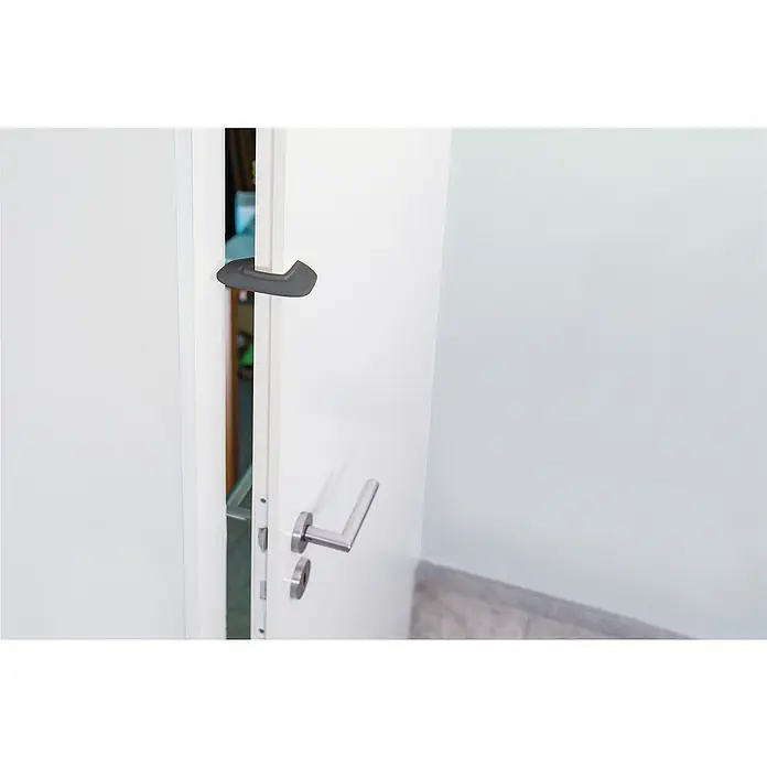 Abus Türstopper Mina - Grau, 2 Stk. - Nahaufnahme eines Türspalts, der mit einem grauen Türstopper gesichert ist und einen Spalt offen hält. Türgriff und Teil des Bodenbelags sichtbar.