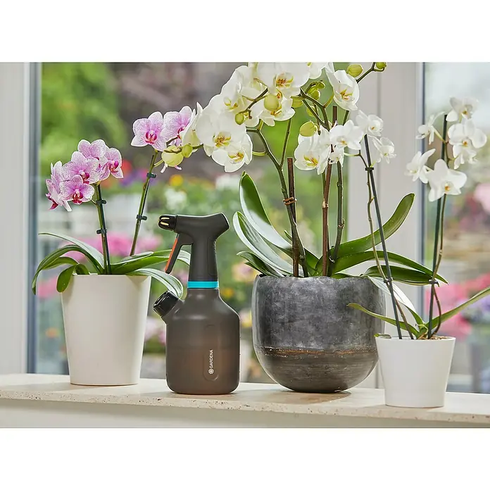 Gardena Handsprüher - 1 l - Der GARDENA Pflanzensprüher, ideal für Zimmerpflanzen, steht zwischen blühenden Orchideen in dekorativen Töpfen auf einem Fensterbrett.