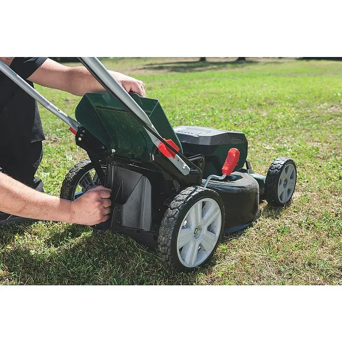 Metabo CAS 18V Akku-Rasenmäher RM 36-18 LTX BL 46 - 18 V, 2 Akkus, 5,2 Ah, Schnittbreite: 46 cm - Eine Nahaufnahme eines Rasenmähers auf einem Rasen, bei dem eine Person den Fangkorb montiert. Das Gerät ist schwarz und grün.
