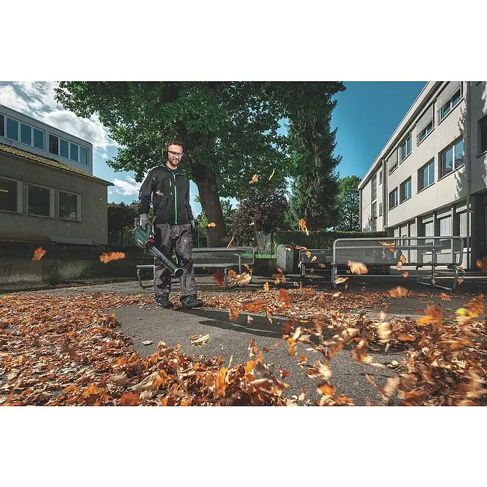 Metabo CAS 18V Akku-Laubbläser LB 18 LTX BL - 18 V, Li-Ionen, 2 Akkus, Blasgeschwindigkeit: 150 km/h - Mann im Freien, der mit einem Metabo-Laubbläser Blätter wegpustet, wobei die Blätter um ihn herumwirbeln.
