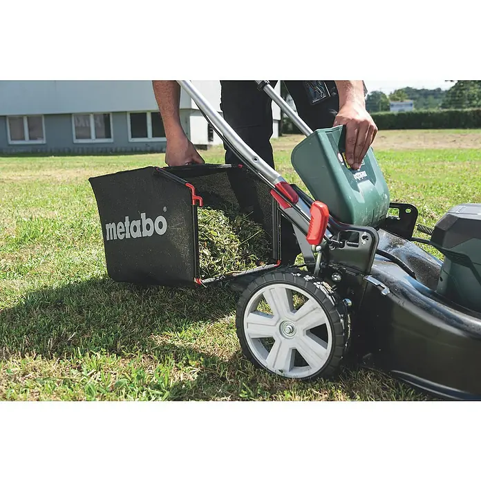Metabo CAS 18V Akku-Rasenmäher RM 36-18 LTX BL 46 - 18 V, 2 Akkus, 5,2 Ah, Schnittbreite: 46 cm - Bild eines Rasenmähers der Marke Metabo mit einem Fangkorb, der mit frisch geschnittenem Gras gefüllt ist.