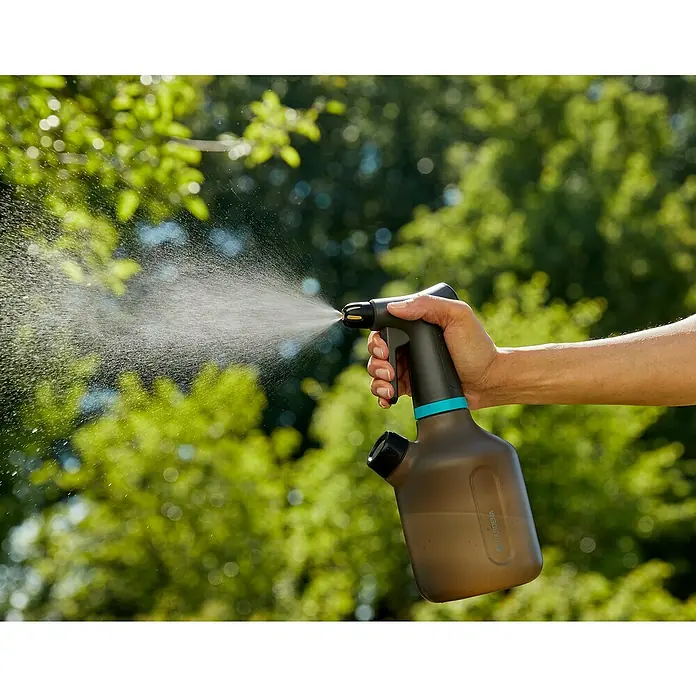 Gardena Handsprüher - 1 l - Eine Hand hält einen Gardena Drucksprüher und sprüht Wasser vor einem grünen Hintergrund.