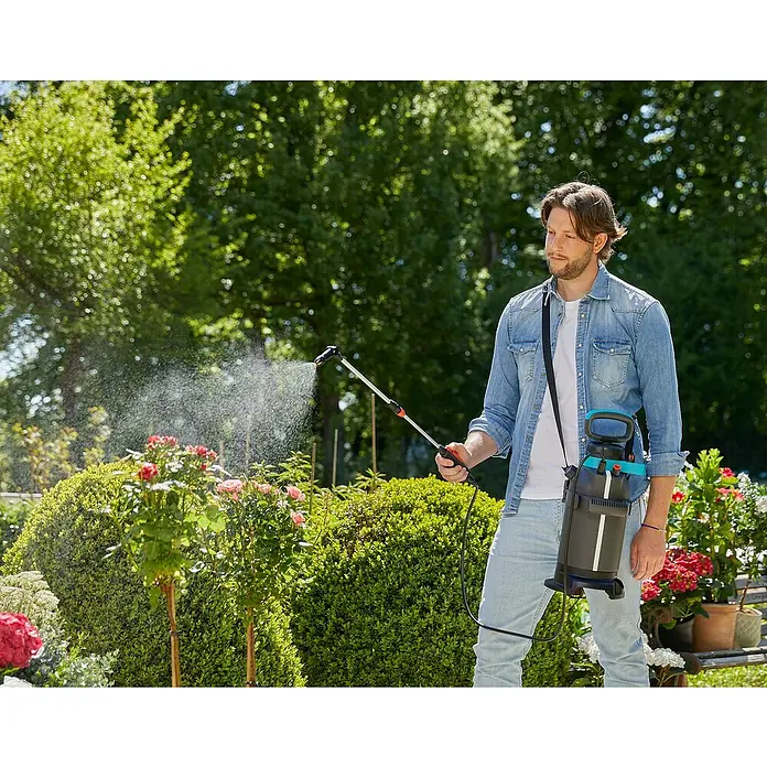 Gardena Drucksprühgerät Plus - 5 l, Gartenspritzmittel - Ein Mann benutzt einen Gardena Drucksprüher zum Gießen von Pflanzen. Das Gerät hängt an einem Gurt um seine Schulter.