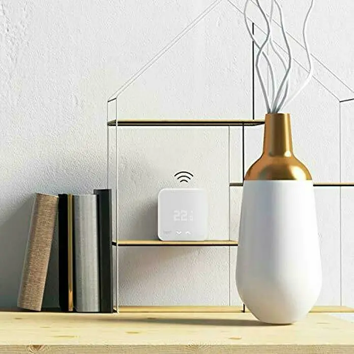 Tado Sensor de temperatura inalámbrico - 1,8 x 10,4 x 10,4 cm, Blanco - Un primer plano de un termostato inteligente blanco en un estante, mostrando tecnología y diseño modernos.