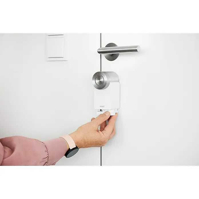 Nuki Akkupack Power Pack - Passend für: Nuki Smart Lock 2.0, Nuki Smart Lock 3.0 & Nuki Smart Lock 3.0 Pro - Nahaufnahme eines Nuki Smart Lock, das an einer Tür befestigt und von einer Hand bedient wird.