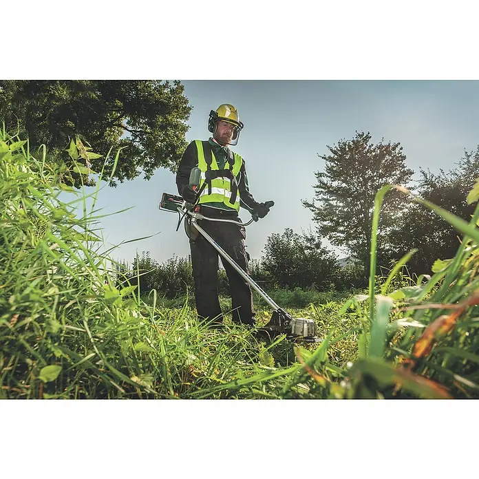 Metabo CAS 18V Akku-Rasentrimmer FSB 36-18 LTX BL 40 - 18 V, 2 Ah, Ohne Akku, Schnittbreite Faden: 40 cm - Ein Mann bedient eine Motorsense, um Gras zu schneiden. Er trägt Schutzkleidung.