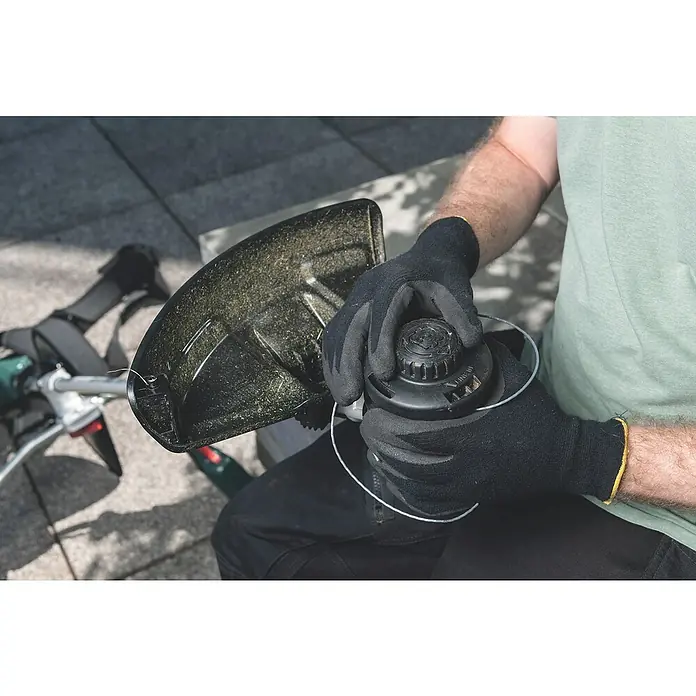 Metabo CAS 18V Akku-Rasentrimmer FSB 36-18 LTX BL 40 - 18 V, 2 Ah, Ohne Akku, Schnittbreite Faden: 40 cm - Eine Nahaufnahme einer Person, die eine Fadenspule einer Rasentrimmers mit Schutzabdeckung und Trimmerfaden in den Händen hält.