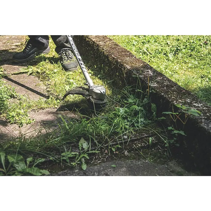 Metabo CAS 18V Akku-Rasentrimmer RTD 18 LTX BL 30 - 18 V, 2 Ah, Ohne Akku, Schnittbreite Faden: 30 cm - Rasentrimmer im Einsatz: Ein Mann trimmt Gras an einem Gehweg mit einem Metabo Rasentrimmer, für präzise Gartenarbeit.