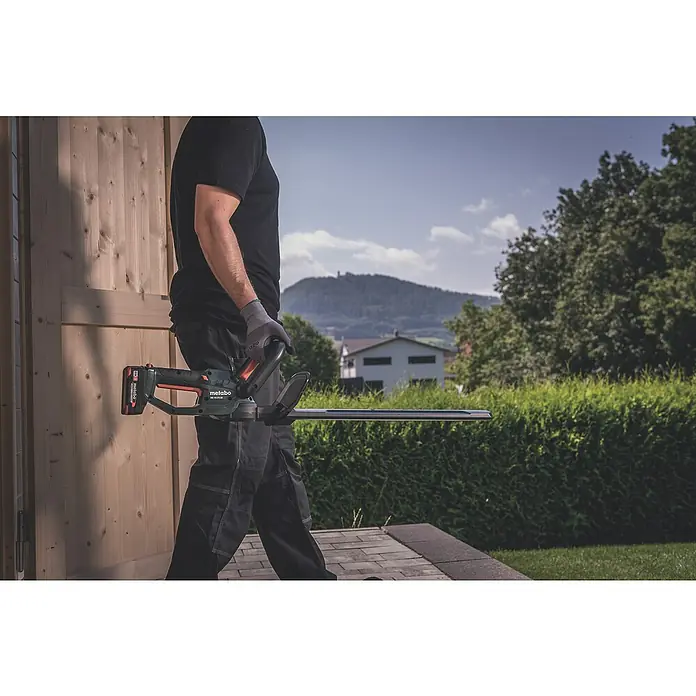 Metabo CAS 18V Akku-Heckenschere HS 18 LTX 45 - 18 V, Li-Ionen, Ohne Akku, Schwertlänge: 45 cm - Eine Person hält eine Metabo Akku-Heckenschere in der Hand, bereit für Gartenarbeiten.
