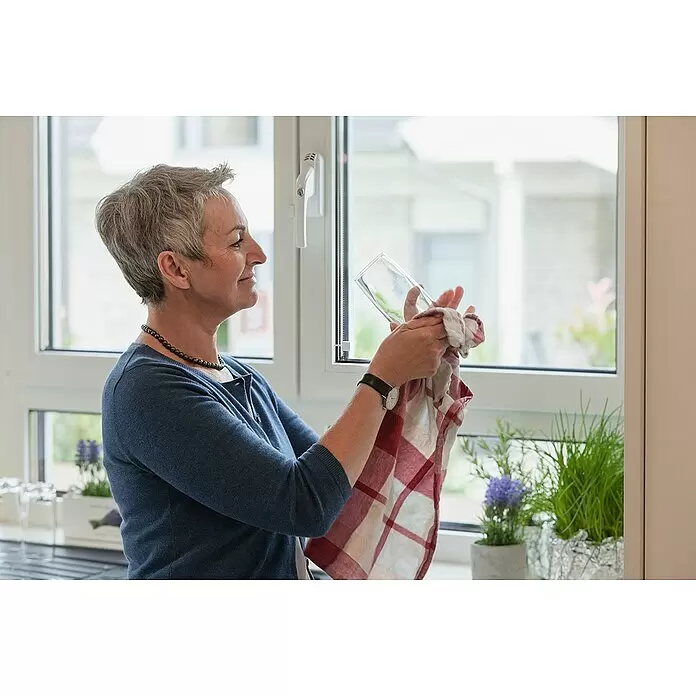 Abus Alarm-Fenstergriff FG300 - Silber - Frau trocknet ein Glas mit einem rot-weiß karierten Geschirrtuch.