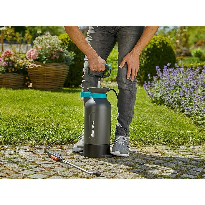 Gardena Comfort Drucksprüher - Füllmenge: 5 l, Grau - Eine Gartenspritze der Marke Gardena steht auf Pflastersteinen, bereit für den Einsatz zur Gartenpflege.