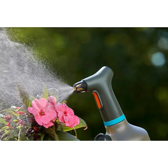 Gardena Handsprüher Easy Pump - 1 l - Eine Gardena-Gießkanne bewässert rosa Blumen. Das Gerät ist grau und hat einen orangenfarbenen Knopf zum Auslösen des Wasserstrahls.