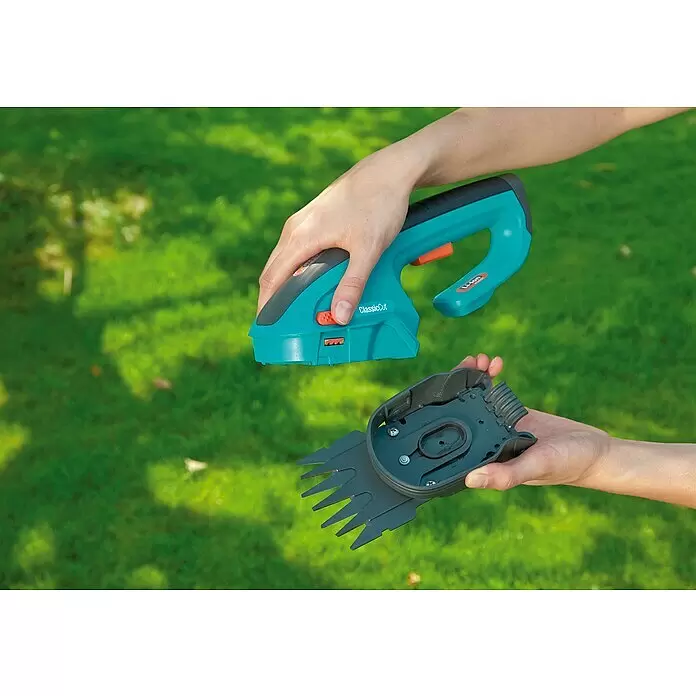 Gardena Ersatzmesser - Passend für: Gardena ClassicCut Akku-Grasschere, Gardena ComfortCut Akku-Grasschere - Hände montieren eine türkis-graue Hand-Gartenschere mit abnehmbarem schwarzem Klingenaufsatz.