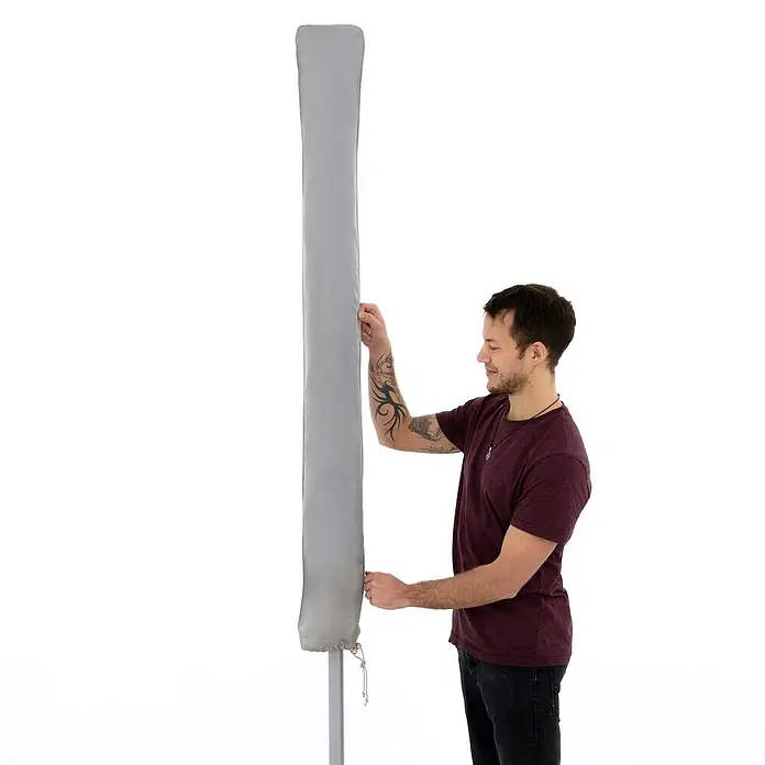 Derby Schirm-Schutzhülle - Passend für: Sonnenschirme bis 350 cm - Eine graue Schutzhülle für eine Wäschespinne wird von einem Mann angebracht, um sie vor Witterungseinflüssen zu schützen.