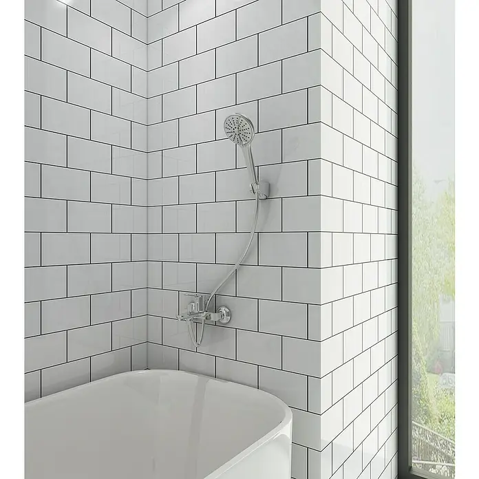 IO Rhio Grifo monomando de bañera - Cromo, Brillante - Primer plano de una bañera moderna con ducha de mano y azulejos tipo metro blancos. El diseño es minimalista y elegante.