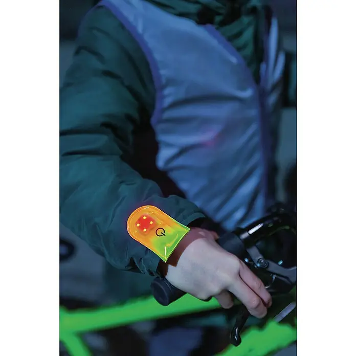 Abus LED-Leuchte Linus - Gelb - Nahaufnahme eines Radfahrers mit einer leuchtenden Armbinde, die für Sichtbarkeit und Sicherheit sorgt.